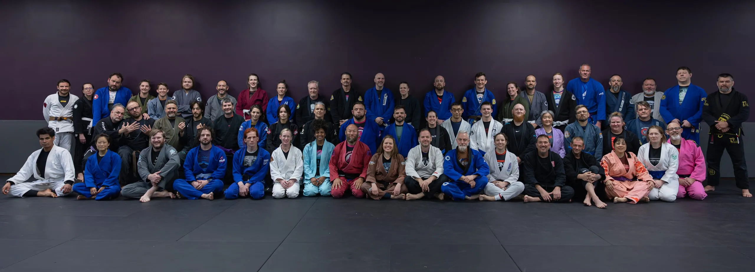 Panoramic group photo of a Brazilian Jiu Jitsu seminar with dozens of practitioners in gis.