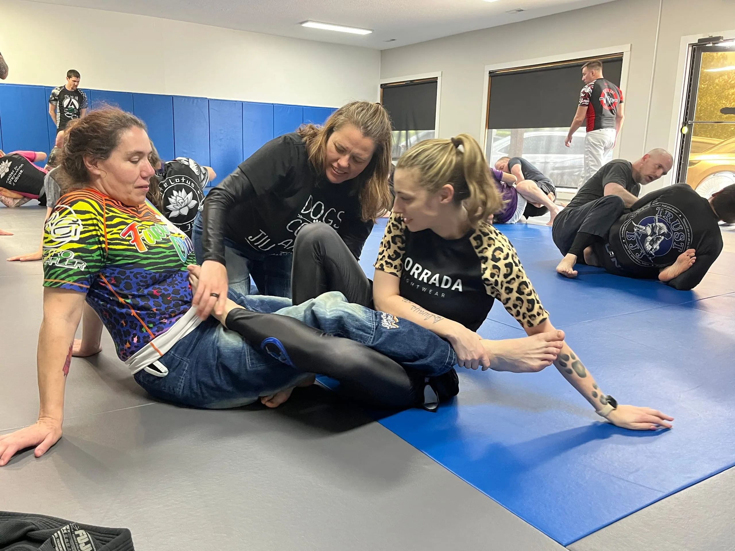 Missy Baize coaches two students through a leg entanglement drill during a no-gi Brazilian Jiu Jitsu class.